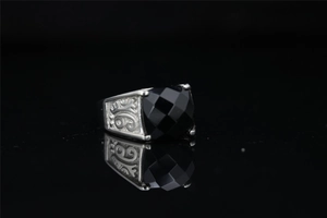 Macro detail of vintage silver ring with black gemstone and intricate scrollwork carvings