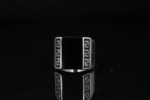 Detailed view of men's silver steel ring with black rectangular inlay and Greek key engraving