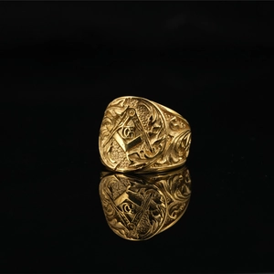 Vintage gold Freemason ring with masonic compass and G symbol on reflective black surface
