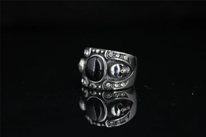 Macro shot of punk gothic steel ring with black gemstone and skull carving details