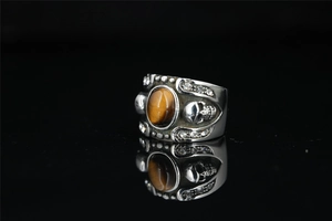 Macro detail of gothic punk ring with brown tiger eye stone and silver skull design