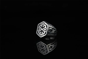 Macro shot of silver ring with hexagonal face featuring celtic knot and relief details