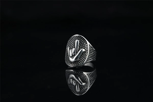 Gros plan d'une bague punk rétro en acier avec relief du geste de la main I Love You pour homme