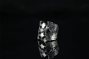 Macro detail of gothic cross ring with eagle wings and central zircon on dark reflection