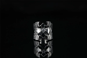 Detailed close-up of a punk style steel ring with cross, wings and clear center stone