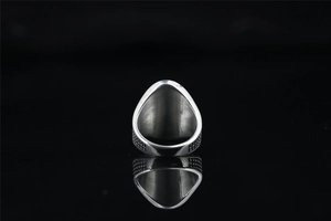 Vue macro d'une bague en titane argenté aux bords texturés sur fond noir poli