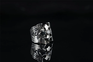 Macro view of gothic punk ring featuring carved eagle wings and a centered cross with zircon