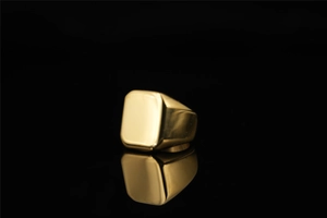 Detailansicht polierter goldener Siegelring mit quadratischer Oberseite auf Reflexion