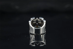 Macro shot of silver punk ring featuring hollowed gothic cross design on black mirror