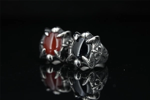 Gothic punk dragon claw rings with black and red oval gemstones on mirror surface