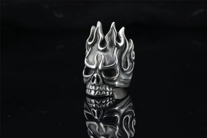 Close-up of vintage punk skull ring with flame patterns on black reflective surface