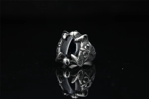 Macro detail of gothic dragon claw ring featuring a large black stone and ornate silver carvings