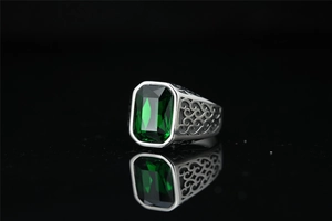 Macro detail of vintage emerald cut green gemstone ring with hollow scroll engraving