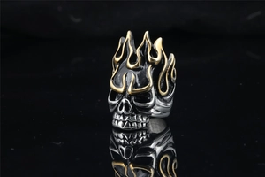Detailed close-up of a vintage punk skull ring with gold flame patterns on black surface