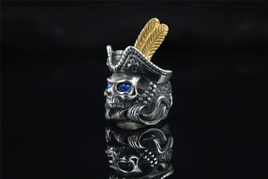 Macro shot of pirate skull ring with gold feathers, blue sapphire eyes and silver finish
