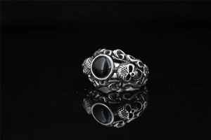 Detail of gothic silver ring with side skull carvings and central black onyx stone inlay