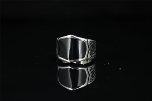 Macro shot of silver titanium ring featuring a black shield face and honeycomb texture