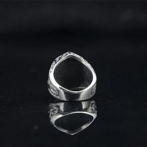 Vintage silver gothic steel ring with intricate carvings on a reflective black base