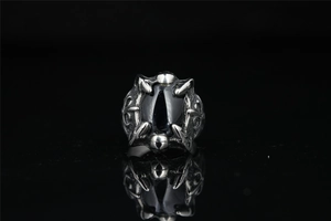 Macro detail of gothic dragon claw ring featuring a large oval black stone and silver metal