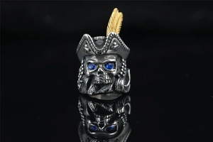 Detail of pirate skull ring with gold feather on hat and blue zircon eye settings