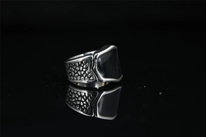 Detail of vintage punk titanium steel men's ring with black stone and scale texture