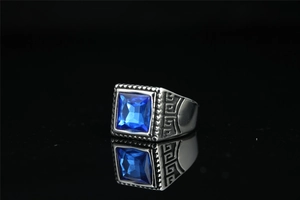 Gros plan sur une bague vintage en acier avec pierre bleue carrée et motifs grecs gravés