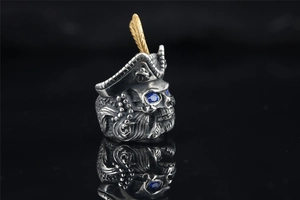 Detailed close-up of a pirate skull ring with gold feather hat and blue gem eyes