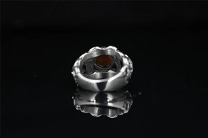 Macro view of vintage silver ring with center dark red stone on black reflective surface