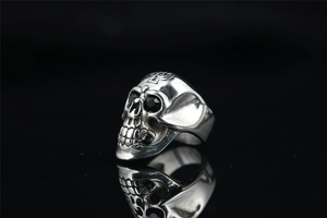 Macro view of vintage silver skull ring with black stone eyes and symmetric reflection