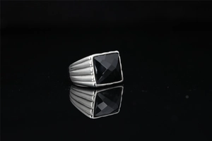 Gros plan d'une bague en acier titane pour homme avec obsidienne noire et texture nervurée