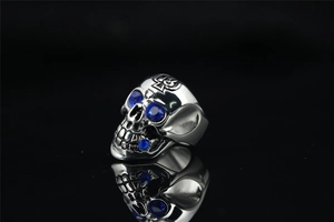 Macro shot of skull ring with blue gemstone eyes and engraved tribal totem patterns