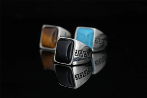 Detailed macro view of retro square signet rings with Greek fret patterns and gemstone inlays
