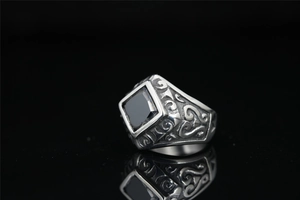 Detailed macro shot of a vintage men's titanium ring with square black gemstone and ornate carving