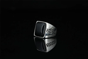 Macro shot of titanium steel ring with black gemstone and Greek Key pattern