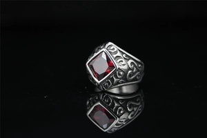 Macro detail of men's vintage steel ring with large square red gemstone and carvings