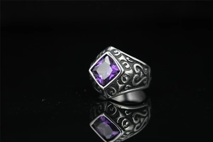 Detailed macro view of vintage men's ring featuring a large purple gemstone and engraved patterns