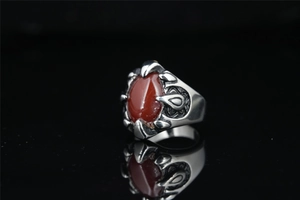 Macro shot of gothic claw ring holding a large red oval stone over black mirror base