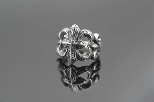 Detailed close-up of vintage silver cross ring with fleur-de-lis engravings on black reflection