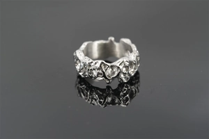 Macro shot of silver titanium steel ring featuring irregular lava texture on dark surface