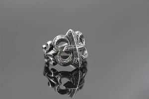 Close-up of vintage silver cross ring featuring intricate fleur-de-lis engravings