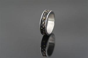 Macro di anello retrò in acciaio al titanio con stelle dorate su finitura nera