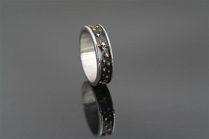 Dettaglio macro dell'anello retrò con stelle in rilievo dorate e finitura nera