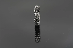 Macro shot of a retro skull relief ring in vintage steel with a black mirror reflection