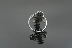 Macro shot of vintage silver cross ring with hollow engraved patterns and mirror reflection