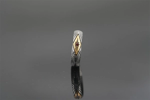 Detailed close-up of retro sunburst ray ring with red gemstone on dark reflective base