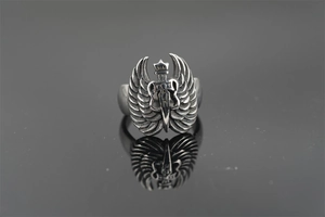Macro detail of punk angel wing ring with vintage sword design on reflective surface