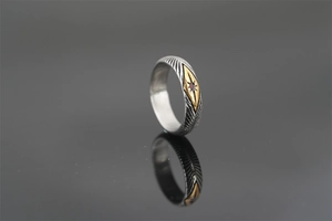 Macro shot of retro sunray texture on steel ring with red stone and golden star inlay