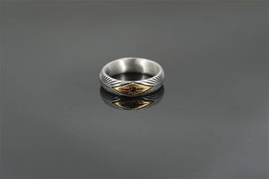 Macro shot of vintage sunray ring featuring feather textures and a red center stone