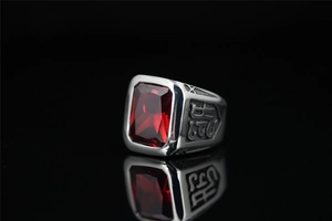 Détail d'une bague pour homme en acier avec une grande pierre rouge et gravures ciselées