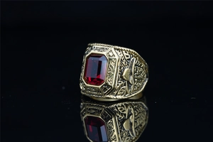 Close-up of vintage gold eagle ring with a large emerald-cut red gemstone on black background